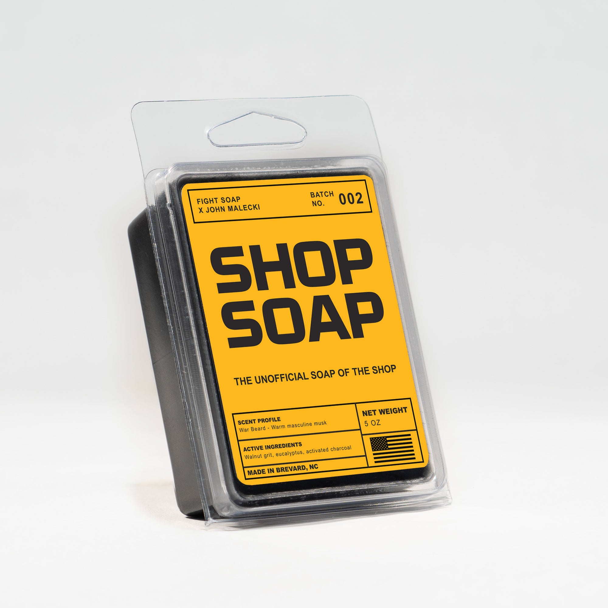 Bar of Shop Soap, a dark charcoal soap bar with visible walnut grit texture.