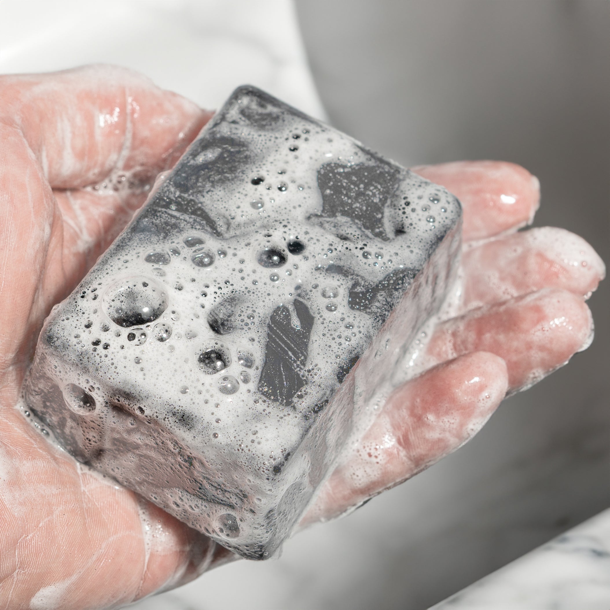 Bar of Shop Soap, a dark charcoal soap bar with visible walnut grit texture.